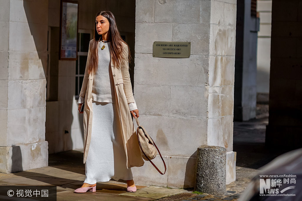 当地时间2017年9月16日，英国伦敦，2018春夏伦敦时装周：潮人街拍（9月16日）。***_***LONDON, ENGLAND - SEPTEMBER 16:  A guest wears a long jacket, a white pull over, a white skirt, pink shoes, a circular bag, outside Simone Rocha, during London Fashion Week September 2017 on September 16, 2017 in London, England.  (Photo by Edward Berthelot/Getty Images)